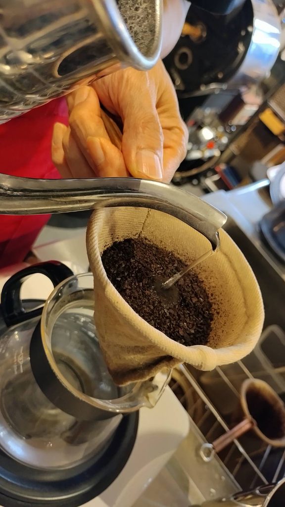 ネルフィルターに入れたコーヒー粉に、ポットからお湯を注いで抽出しているところ