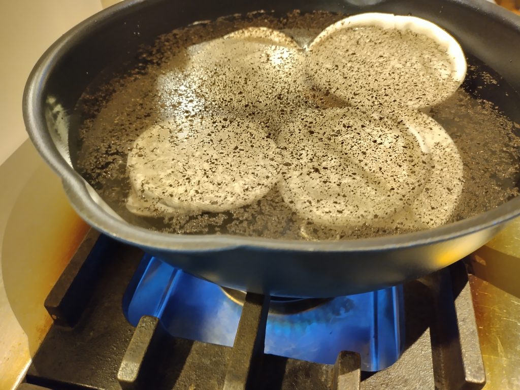 ガスコンロにかけた鍋で、挽いたコーヒーの粉と一緒にネルフィルターを煮ているところ